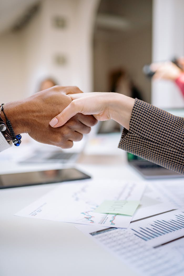 gallery-02 Close-up of a professional handshake over business documents, symbolizing partnership and agreement.