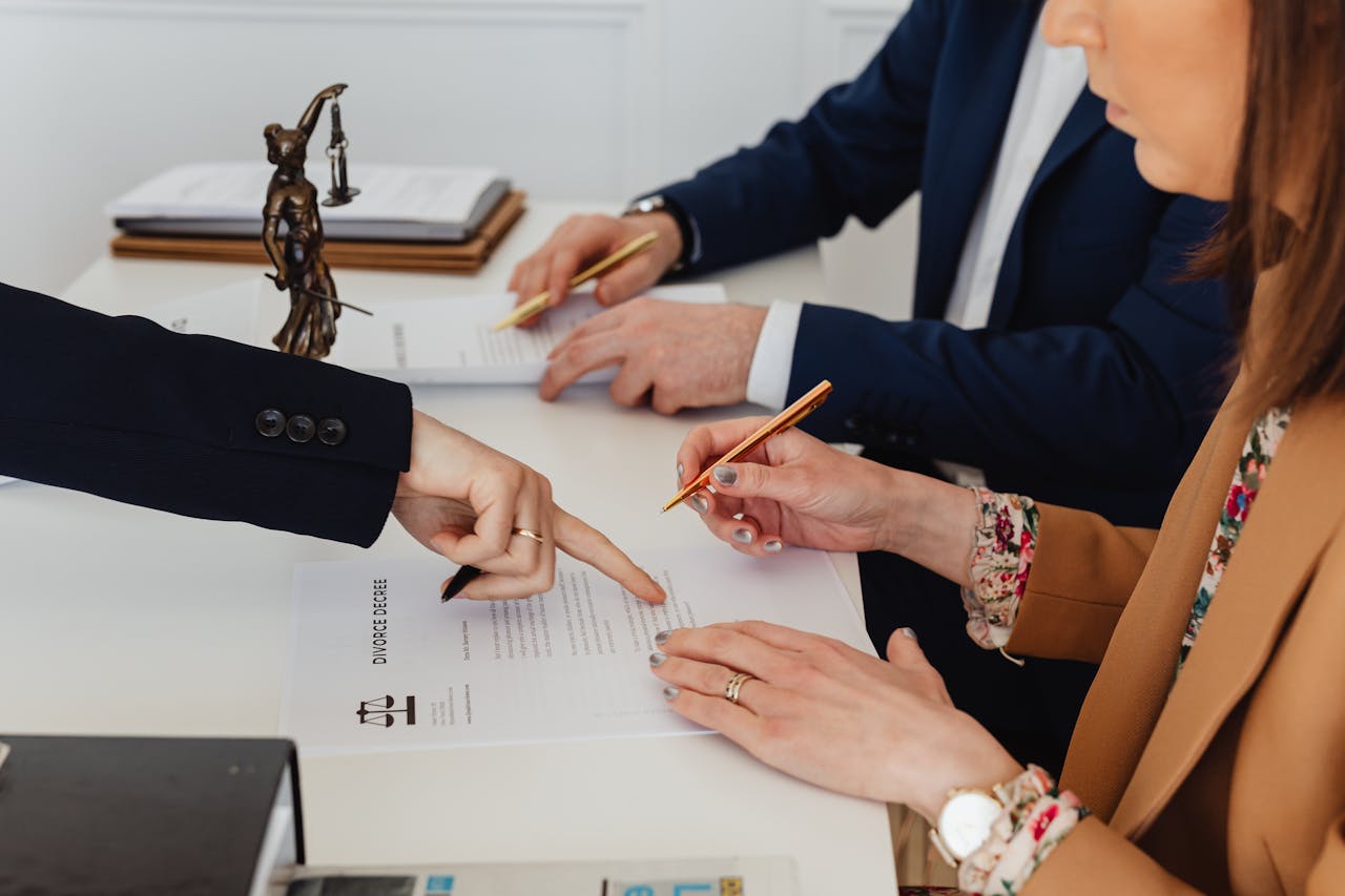 home-img Hands signing a divorce decree, with a justice statue nearby, symbolizing legal proceedings.